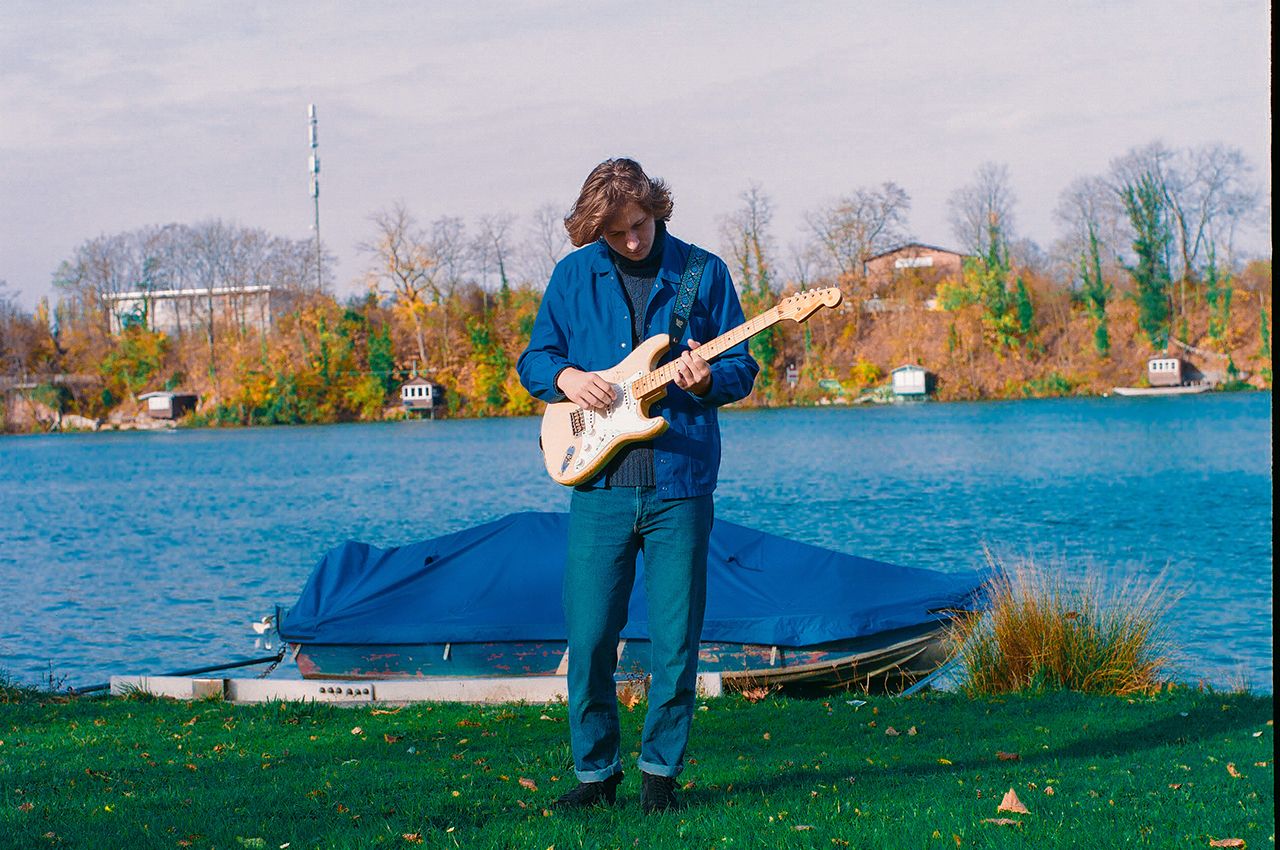 Thibaut Stepczynski mit Gitarre am Flussufer