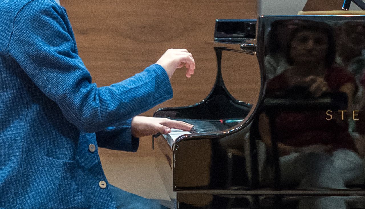 Ein Junge in blauem Anzug spielt Klaver