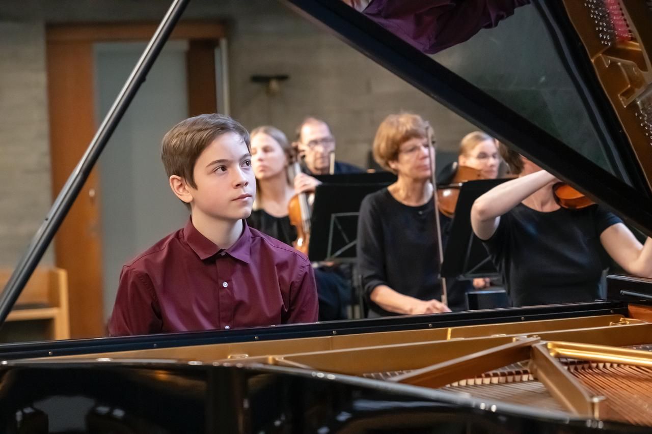 Der 14-jährige Maurice Providoli am Flügel, hinter ihm das Reinacher Orchester